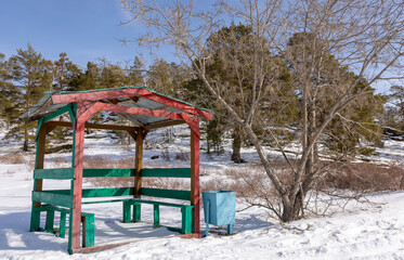 a red wooden gazebo stands in the mountains in winter

