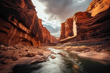 Zelfklevend Fotobehang A dramatic canyon landscape, with towering red rock formations, deep crevices, and a meandering river winding its way through the rugged terrain. © Hashmat
