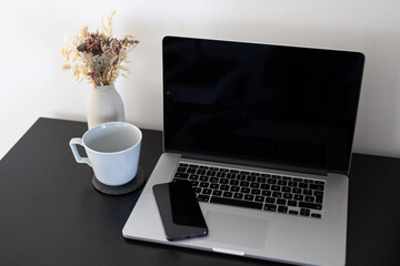 Laptop with smartphone, coffeemug and flowers