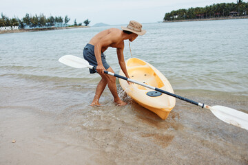 Exhilarating Kayaking Adventure: A Happy Asian Man Paddling a Kayak on a Tropical Beach