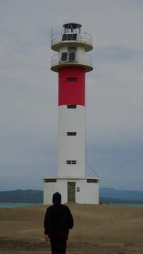 Persona caminando hacie el Faro del Fangar con el mar de fondo