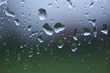 Raindrops on a window pane after heavy rain with background thrown out of focus. Suitable as a background.