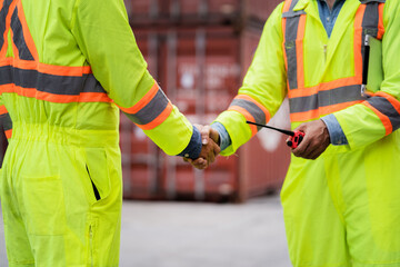 Two male workers shake hands to agree to work on a job site or in a factory. The scene is...