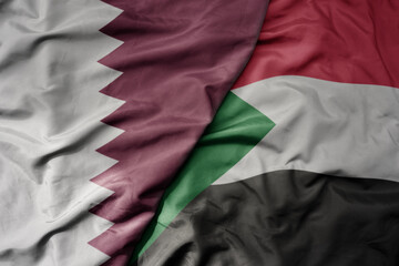 big waving national colorful flag of sudan and national flag of qatar.