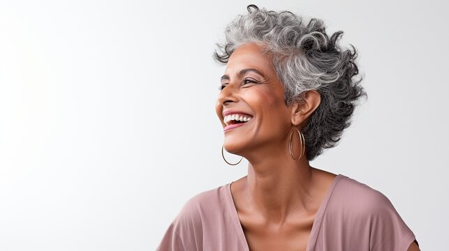 Closeup photo portrait of a smiling senior south Asian woman on a light grey background
