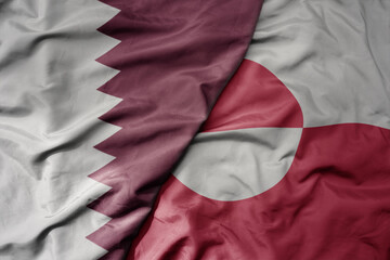 big waving national colorful flag of greenland and national flag of qatar.