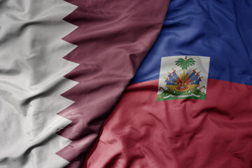big waving national colorful flag of haiti and national flag of qatar.