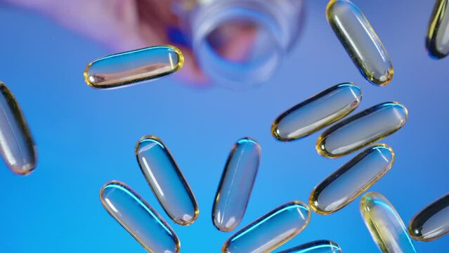 Medical capsules spill out of a transparent plastic container jar on a transparent table glass surface