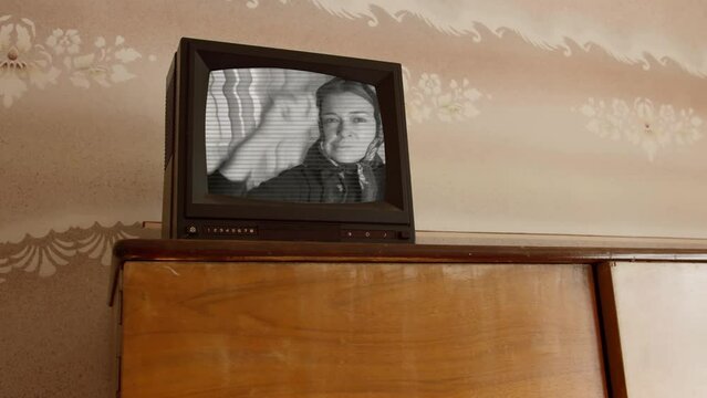 Old black and white retro TV on the cabinet the girl on the screen calls for action