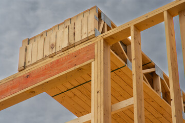 Floor joists stacked on top  of first floor of  multi story wood frame apartment building under construction. - obrazy, fototapety, plakaty