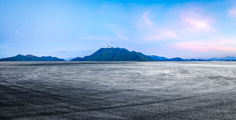 Empty asphalt road and mountains with city skyline