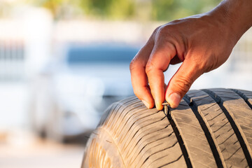 The mechanic was using his hands to remove a nut ro nail from a tire that had been stepped on and caused a puncture. Accidents while driving on the road concept