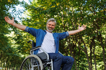 Fototapeta premium Park Pleasures: Man in Wheelchair Engaging with Open Arms