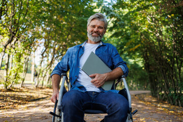 Fototapeta na wymiar Digital Nomad Accessibility: Wheelchair-bound Man Using Laptop