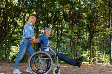 Woman in Mask Supports Man in Wheelchair Outdoors