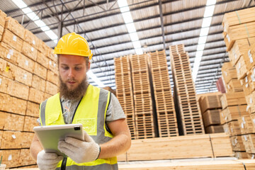 Worker Man with a bearded wearing safety uniform yellow hard hat using tablet working checking...