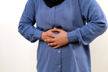 Close up photo of Asian muslim woman suffering from stomachache. Hand holding stomach