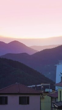 The setting sun illuminates the roofs of a medieval town in the mountains. Perinaldo, Italy.