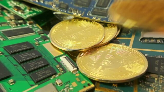 Close up pile bitcoins coins spill onto table next to microcircuits. Bitcoin mining concept. Cryptocurrency gpu farms equipment. 
