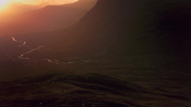 Winding river and mountains illuminated by the rising sun. A82 road opposite Buachaille Etive Mor at dawn. Scotland. Panning forwards
