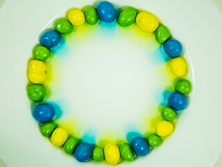 Colored oder grüne, gelbe und blaue  Schokokugeln liegen im Wasserbad und verlieren Farbe.