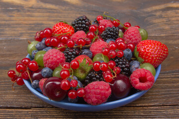 Various summer Fresh berries in a bowl on rustic wooden table. Antioxidants, detox diet, organic...