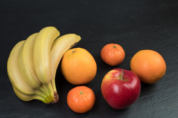 Fruits. Bananas, apples, oranges, tangerines on a black background.