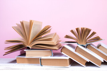 Open books, hardback colorful books on wooden table. pink background. Back to school. Copy space for text. Education business concept.