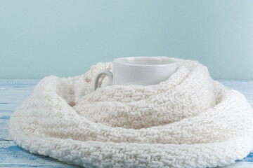 Top view image of white cozy knitted sweater with to cup of coffee on a wooden table.