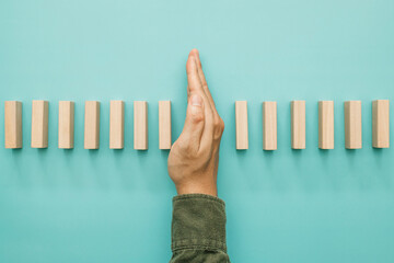 Business risk management concept. Businessman stopping the domino effect on wooden table. Business...