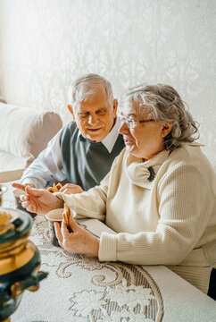 Elderly senior romantic love couple drinking tea with cookies from samovar. Old retired man woman together. Aged husband wife in cozy home. Elder people. Happy family longevity. Tender relationships
