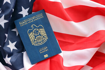 Blue United Arab Emirates passport on United States national flag background close up. Tourism and diplomacy concept