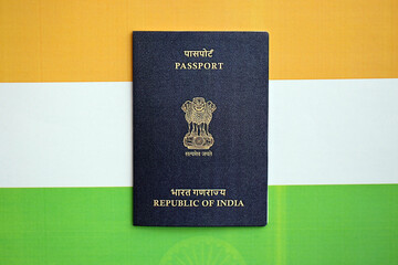 Blue Indian passport on national flag background close up. Tourism and citizenship concept