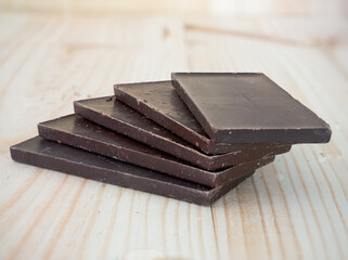 bar sheets of dark cocoa chocolate layered on a wooden board