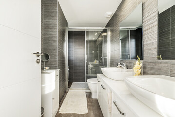 A conventional bathroom with white wooden furniture, with double porcelain sinks above the dresser,...