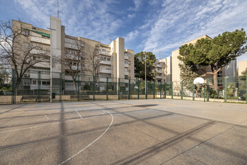 Urban youth recreation area on a basketball court with rough cement floors and baskets on metal posts bolted to the ground
