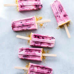 Cherry yogurt pops on a light rustic surface on a bright sunny day.