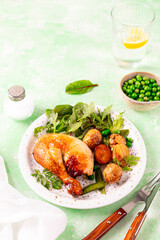 Baked chicken with baby potatoes and salad on a green background.