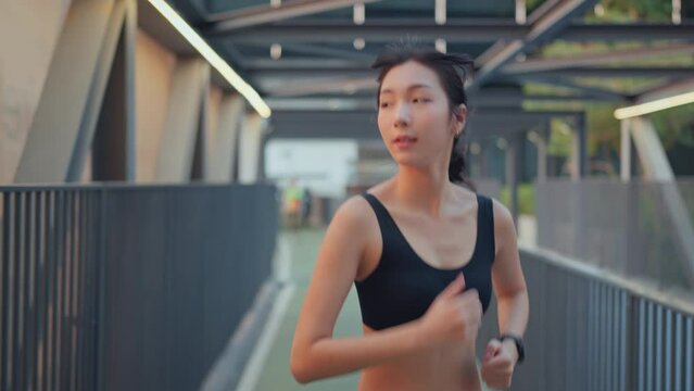 Young asian woman runner is training in the summer sunset within a city, The athlete fit and firm girl exercising by jogging workout sport outdoor for her healthy wellness.