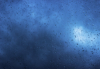 Rain drops on the window surface, dark blue clouds visible through the rain. Rainy background