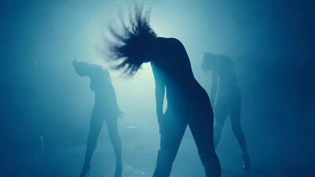 Captivating shadows of a dance group on high heels amidst moody, blue stage lighting, depicting motion and energy.