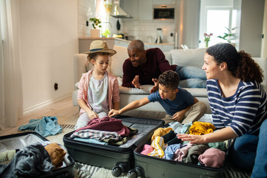 Family packing suitcase together for vacation in living room