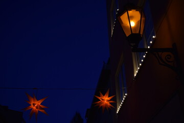 Yellow street lamp and star shaped Christmas lights - obrazy, fototapety, plakaty