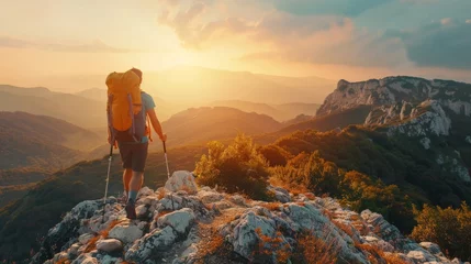 Tuinposter Male hiker with backpack walking on top rock mountain landscape and beautiful view sunset background.Hiker men's hiking living healthy active lifestyle. © Sasint