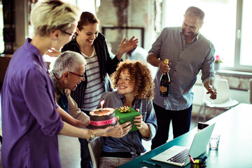 Colleagues celebrating birthday with cake and champagne in startup office