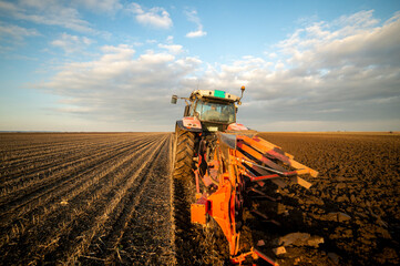 The tractor is working in the field, preparing the soil in autumn after the harvest