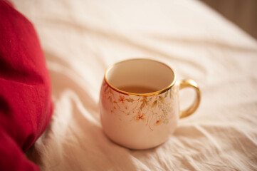 A cozy pink cup of coffee sits on a morning bed, radiating warmth and tranquility in a serene ambiance