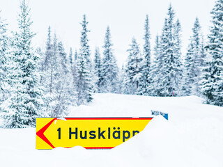 Winter Road Sign Indicating Huskläppen Amidst Snow-covered Trees in Sweden