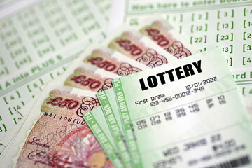 Green lottery tickets and Great Britain pounds money bills on blank with numbers for playing lottery close up