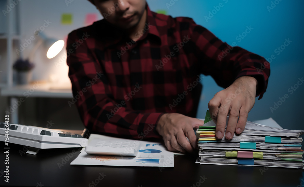 Poster A man is sitting at a desk with a stack of papers in front of him